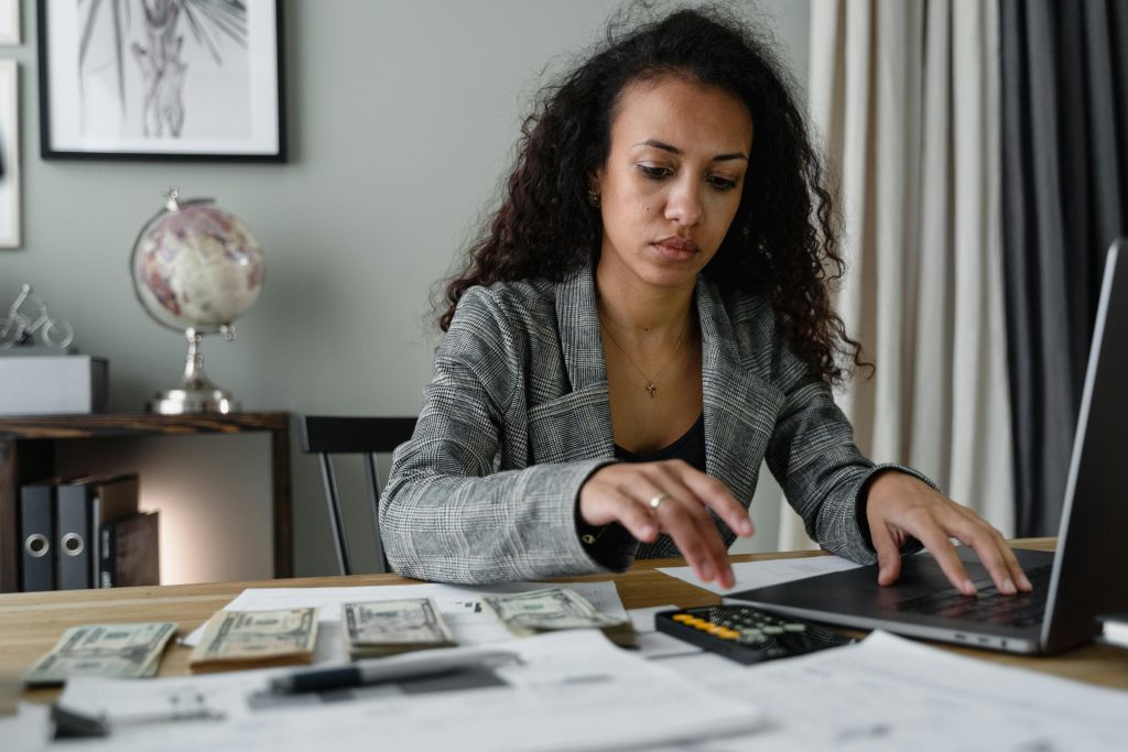 beauty studio owner reviewing business finances with calculator and laptop