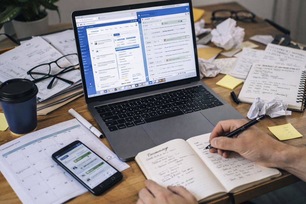 small business workspace using laptop phone and notebook showing multiple tools and fragmented workflow